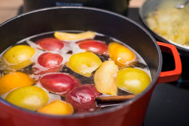 Preparing hot apple cider in a red saucepan. Close up. stock photo
