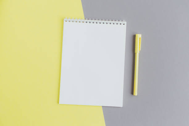 istock Notebook with blank page and pen on a grey and yellow background. 1290749370