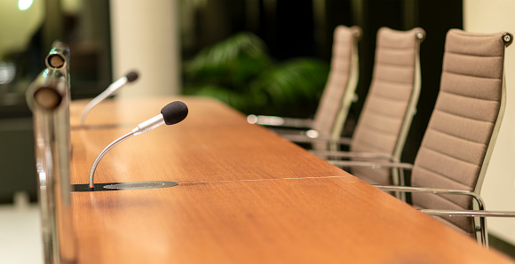 Vista aislada de un micrófono en la parte delantera de una sala de conferencias entre otros micrófonos borrosos en el fondo photo