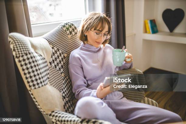 Young Woman Relaxing With A Book And A Cup Of Coffee At Her Home Stock Photo - Download Image Now