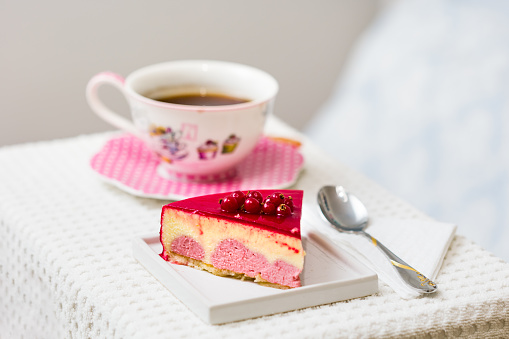 Red berries and vanilla cream cake with a cup of tea - coffee as background. Tea time concept.