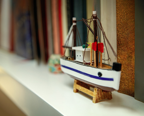 Small wooden ship on a bookshelf, travel - nostalgia concept.