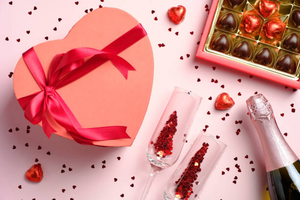 istock Happy Valentines day concept. Flat lay romantic composition with heart shaped box decorated red ribbon bow, sweets, champagne and glasses on pink background. 1290760858