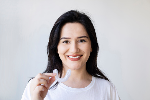 Primer plano de la mano de una mujer poniendo un alineador transparente en los dientes photo