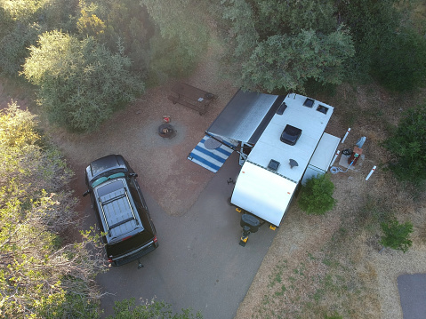Campsite campground with a travel trailer and SUV looking down from drone