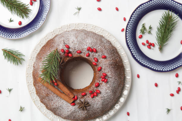 istock Festive bundt cake decorated with red berries and fir branches on white background. 1290770076