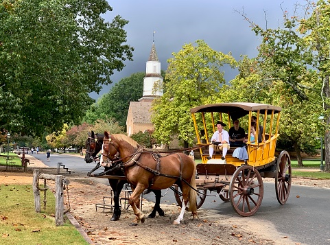 Williamsburg, VA, USA - September 29, 2020: Tourists are enjoying horse drawn carriage ride in Williamsburg, Virginia, USA.