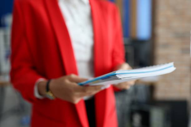 istock Woman in red jacket holds documents in her hands closeup 1290775497