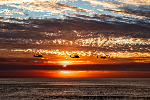 Three Helicopters flying over Beautiful California Ocean Sunset