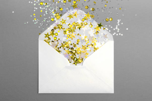 istock Sparkling confetti scattered from envelope on gray background. 1290783450