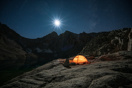 Tent Camping at Consultation Lake with clear night sky full of stars surrounded by snowy mountains on the way to the summit of Mount Whitney in the Californian Sierra Nevada