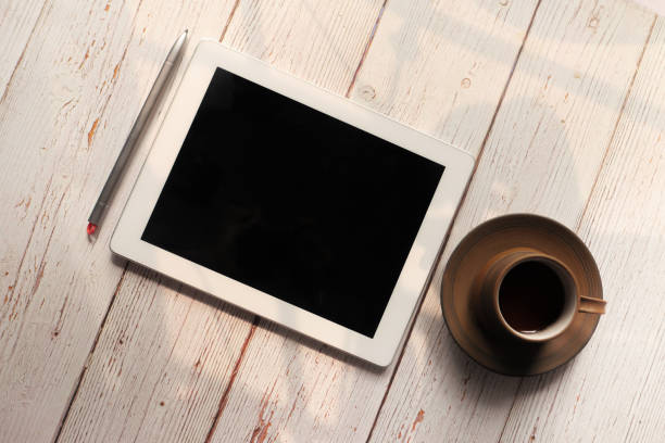 Flat composition of digital tablet and tea on wooden background .