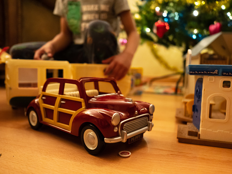 Asian kid opening Christmas presents and he gets a vintage toy car as a gift.