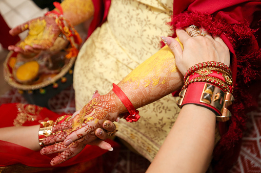 A focus scene of traditional Indian (Hindu) wedding - family member rubbing turmeric paste on bride-to-be's hand for glow in Kuala Lumpur, Malaysia.