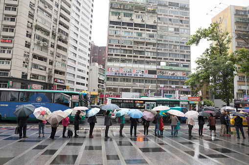 Taipei, Taiwan, May 2019: long line of people with umbrellas are waiting for transportation.