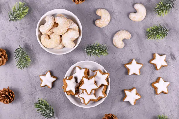 Top view of white bowls with traditional German and Austrian Christmas cookies, one filled with cinnamon star cookies, the other with crecent shaped almond cookies