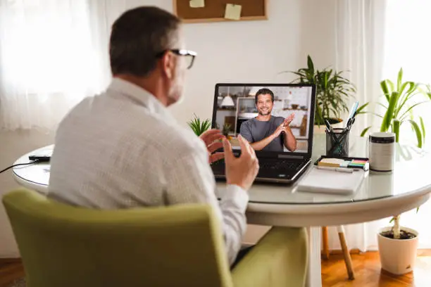 Photo of Deaf man talking using sign language on the laptop at home.