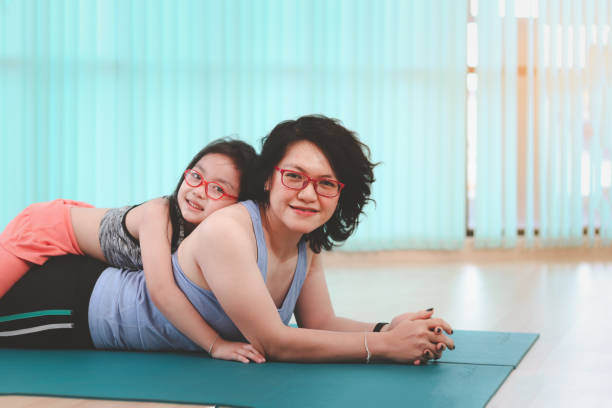 Mother and daughter lying down together for rest before doing yoga pose, girl riding on her mom madre e hija acostados juntos para descansar antes de hacer la pose de yoga, chica montando sobre su mamá