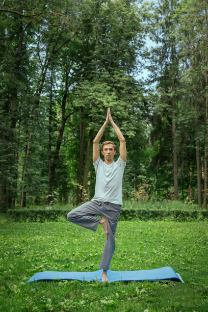 istock Fitness, man training yoga in tree pose in park 1290825144