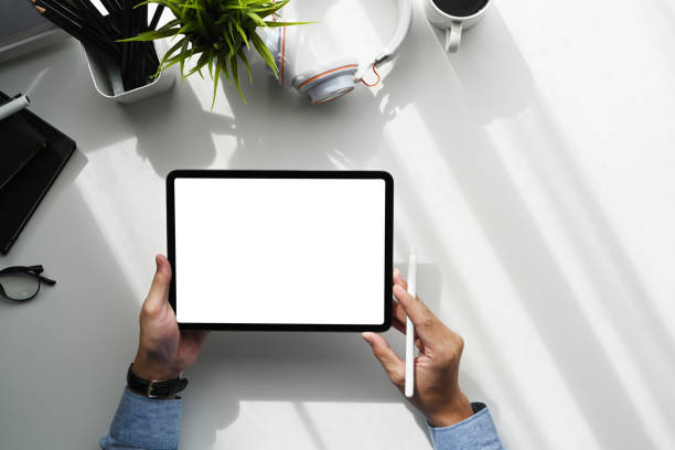 istock Over head shot of graphic designer using digital tablet on white table.Blank screen for graphics display montage. 1290827694