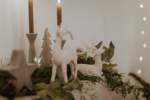 Christmas decorations with deer and candles, fir branches and green plants.