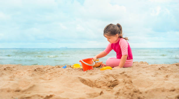 istock Girl on the beach playing in the sand. 1290833359