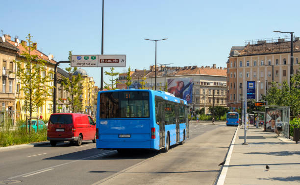 Bela Bartok Street in Budapest, Hungary. Sunny summer day on a street in Budapest. A wide avenue occupied by a blue city bus. bus hungary stock pictures, royalty-free photos & images