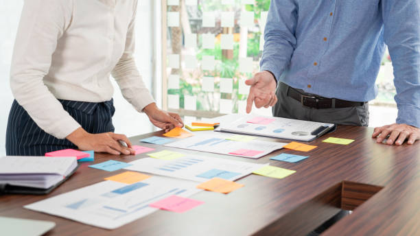 Businessman stick colorful notes to brainstorming on the table working on new project to share idea to thinking how to planning new case.