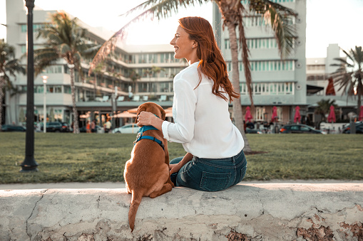 Woman relaxing on Miami Beach Ocean Drive promenade with her puppy