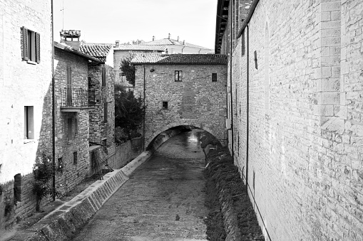 A medieval house with an arch under which a small stream flows in an Italian village (Gubbio, Italy, Europe)