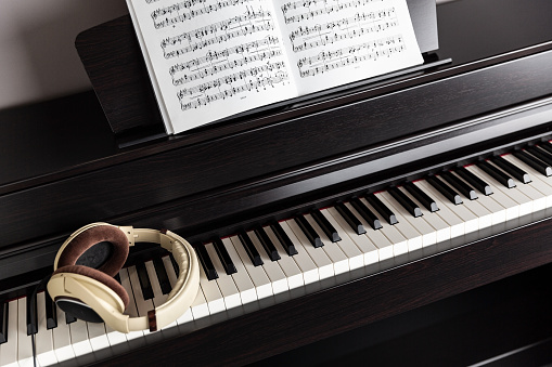 Electric piano (clavinova) keys, headphones and sheet music