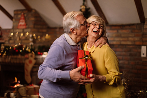 Older woman receiving a present and a kiss from her husband on Christmas