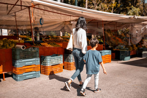 Mother and son enjoying the walk Family enjoying the sunny day. As a weekend activity, they choose to visit the farmers market agricultural fair stock pictures, royalty-free photos & images