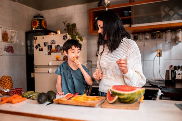 istock Mother cutting fruit and son is eating it 1290849121