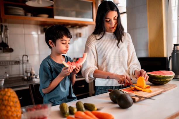 istock Mother cutting fruit and son eating watermelon 1290849707