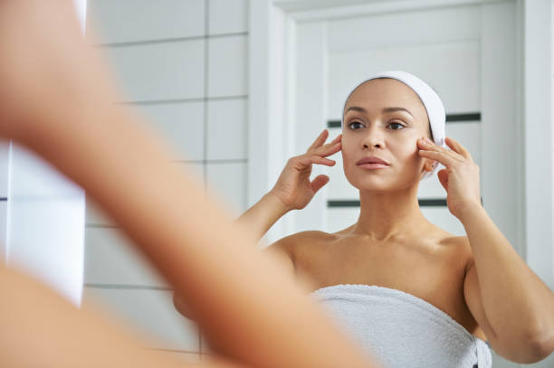 istock Young woman doing face massage in front of the bathroom mirror 1290849836