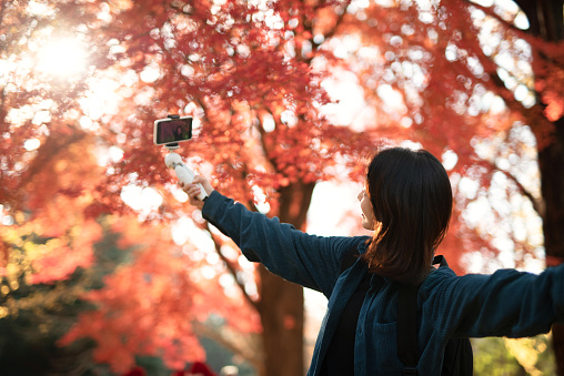 Asian young woman vlogging from the Autumn park