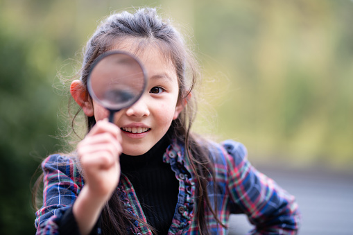 Girl playing with a magnifying glass