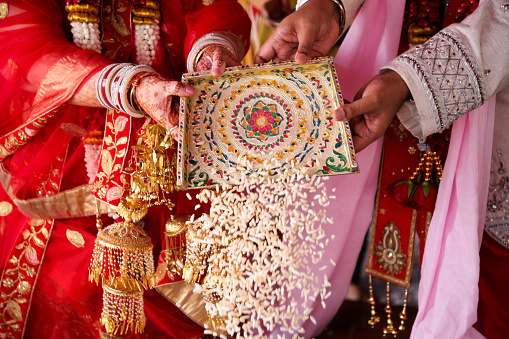 A focus on traditional north Indian (Hindi) wedding ceremony - bride and groom pouring rice into sacred fire in Kuala Lumpur, Malaysia.