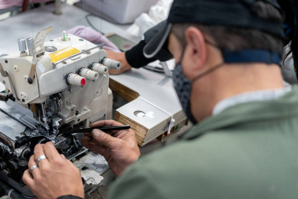 mann arbeitet in einer textilfabrik und macht wartungsarbeiten an einer nähmaschine - preventative maintenance stock-fotos und bilder