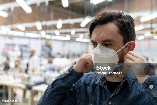 Man Working Textile Factory During The Covid19 Pandemic And Fixing His Facemask Stock Photo - Download Image Now
