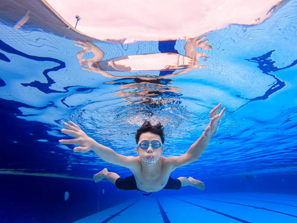 under water view asian chinese teenage boy swimming in swimming pool under water view asian chinese teenage boy swimming in swimming pool underwater camera stock pictures, royalty-free photos & images