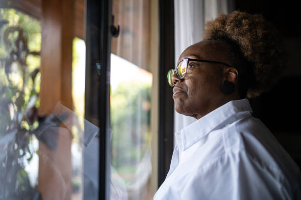 istock Senior woman looking through the window 1290862561