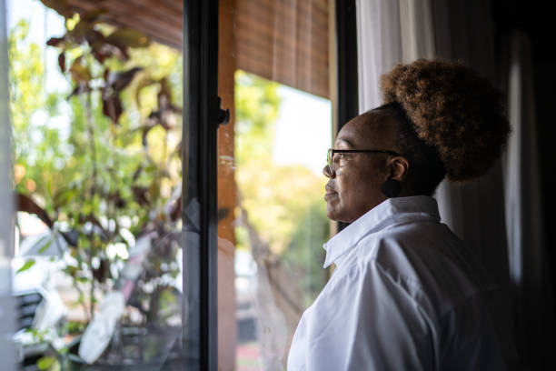istock Senior woman looking through the window 1290862653