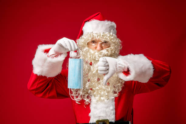 istock Santa Claus holding protective face mask showing thumbs down. 1290863704