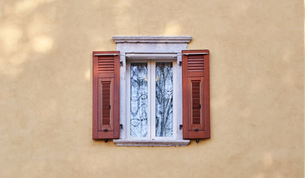 ventanas italianas en la fachada de la pared de color arena amarillo con nuevas persianas de color rojo-marrón de madera modernas - wood shutter rusty rust fotografías e imágenes de stock