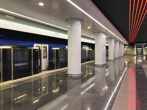 Nearly empty urban metro station with departing train.