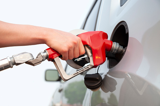 Isolated arm and hand of a young man pumping gas into his car