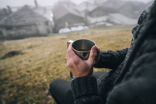 istock Young man in grassy meadow sips on tea in the morning 1290877670
