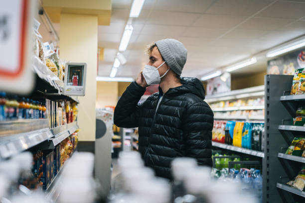 istock Young man wearing protective face mask shops in grocery store 1290877700
